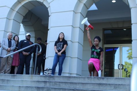 AUSG President Taylor Dumpson kneels with a megaphone in her hand at the rally.