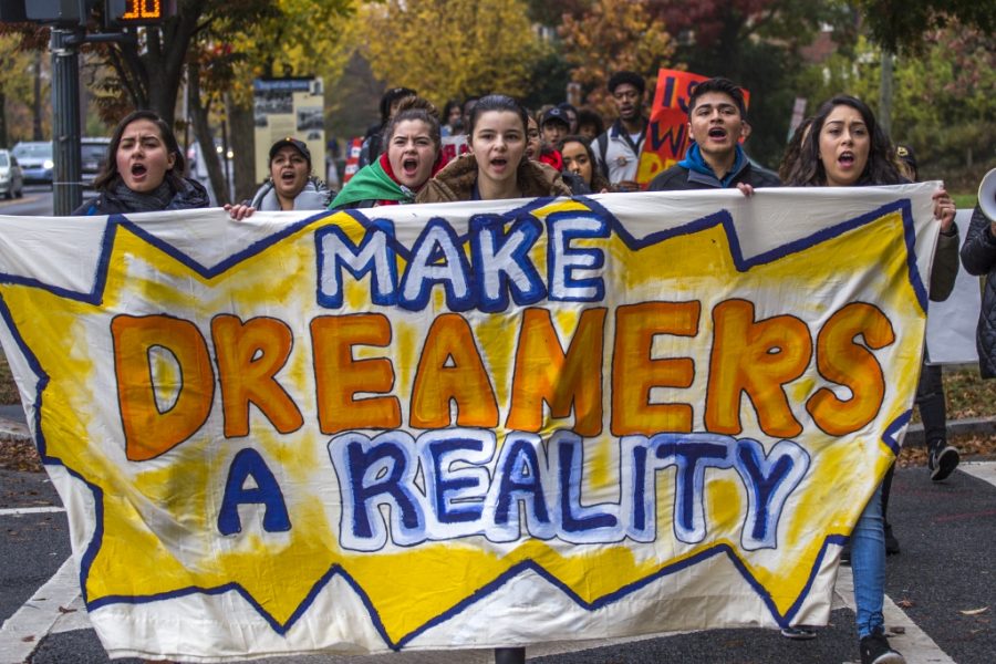 Protesters marching down the street with a banner that reads, Make Dreamers a Reality. 
