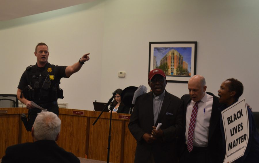 Montgomery County Police Officer, Chris Hackley, reads a statement ordering protestors to leave the public forum. Macedonia Baptist Church pastor Segun Adebayo, Somerset Mayor Jeffrey Salvin, and Lucile Perez refused to leave; they were arrested and charged with disorderly conduct.  