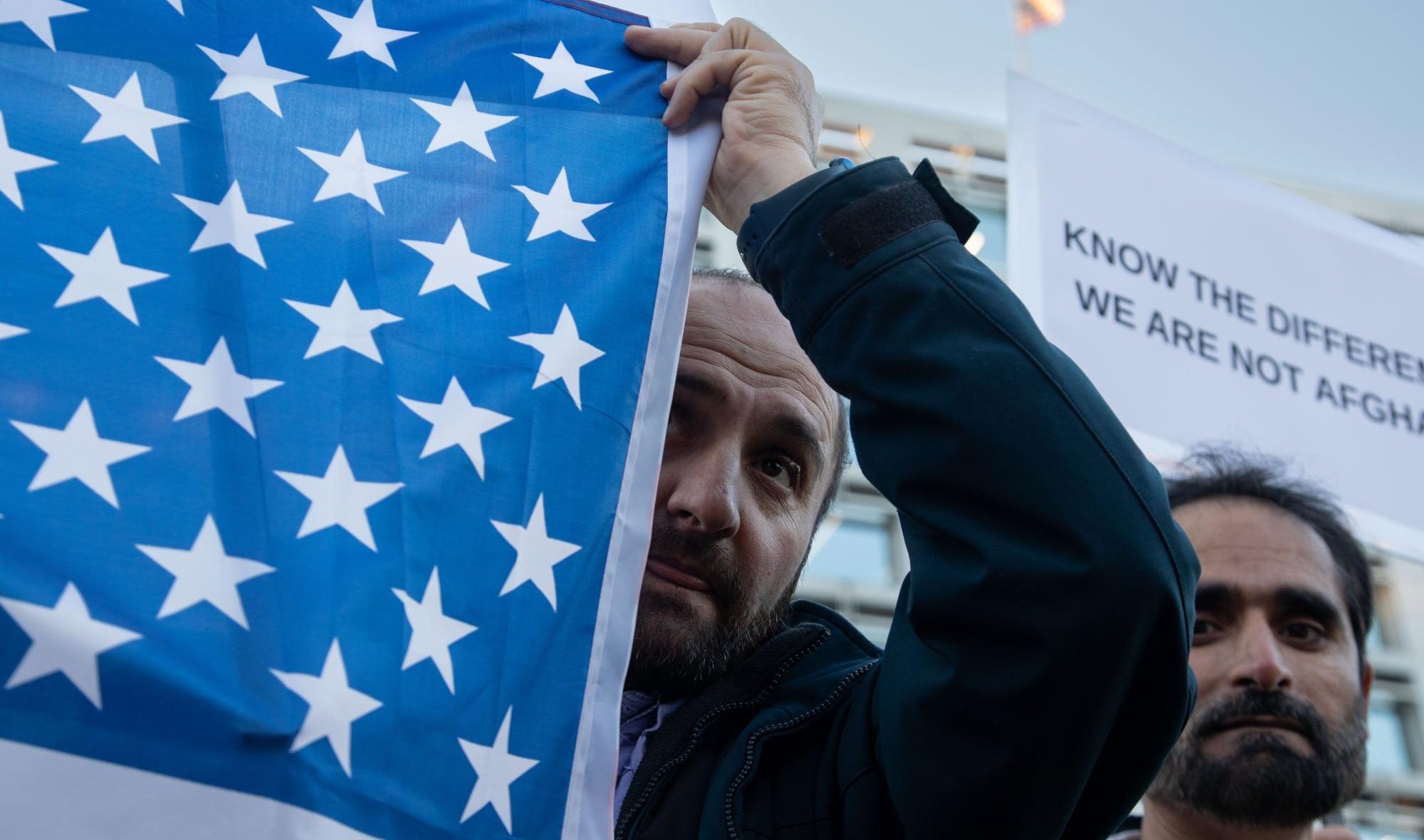 A protestor lifts a corner of an American flag at Farragut Square.